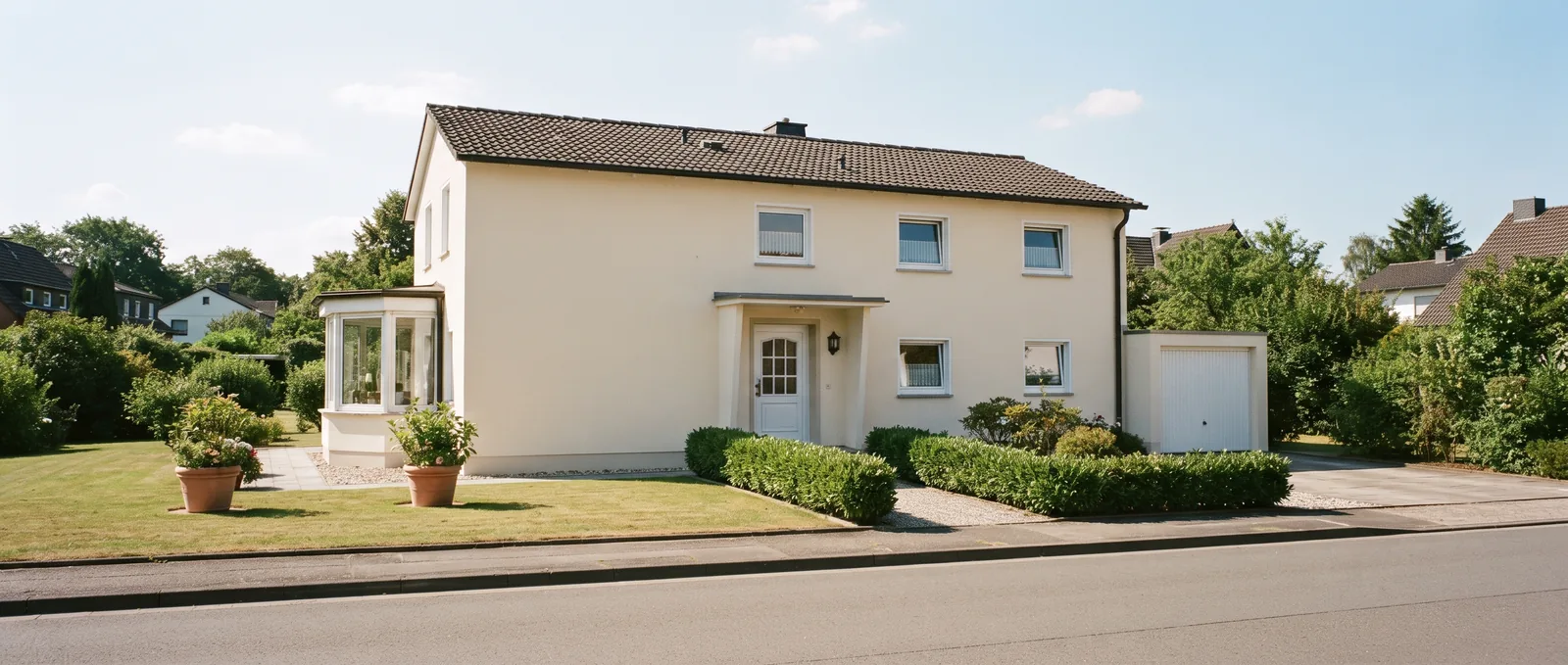 Gepflegtes Einfamilienhaus mit heller, gleichmäßig verputzter Fassade und sonnigem Vorgarten